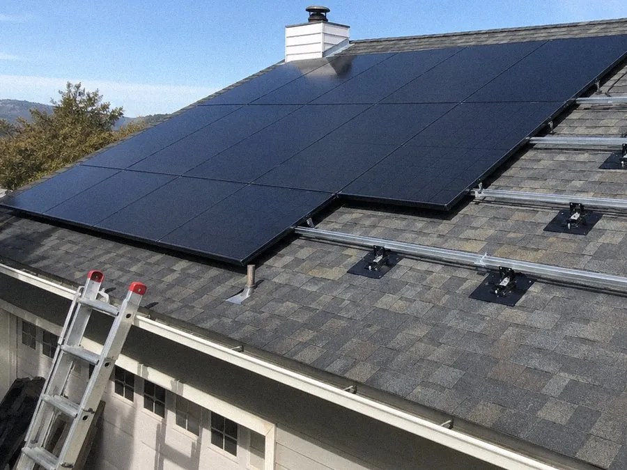 Row of installed solar panels and mounting rails seen from the roof edge