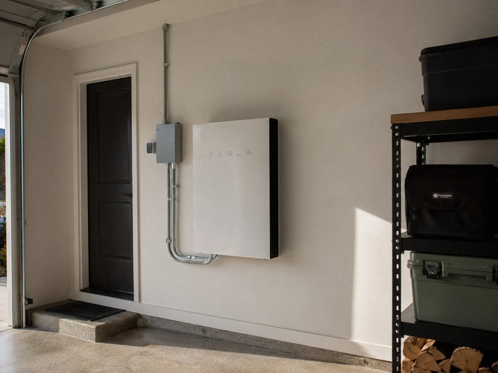 Wall-mounted home battery with clean conduit runs in a garage