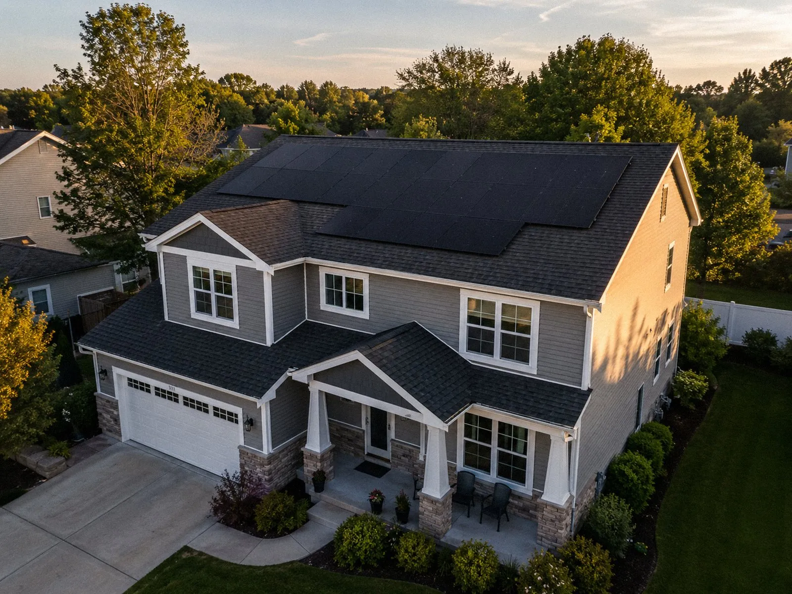 Aerial view of a large two-story suburban home with a rooftop solar array installed across multiple roof planes